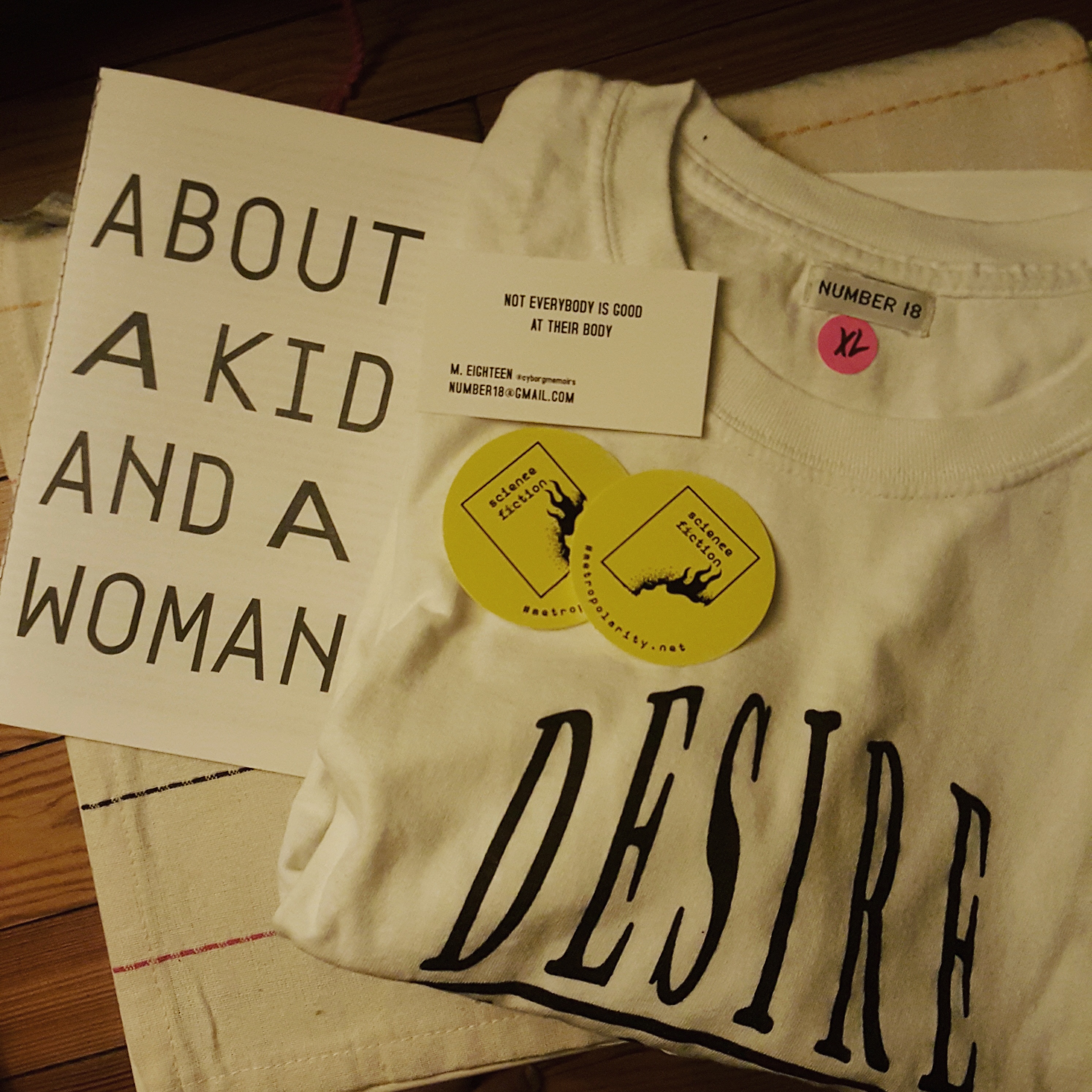 zine with a folded tee, stickers and biz card in a pile