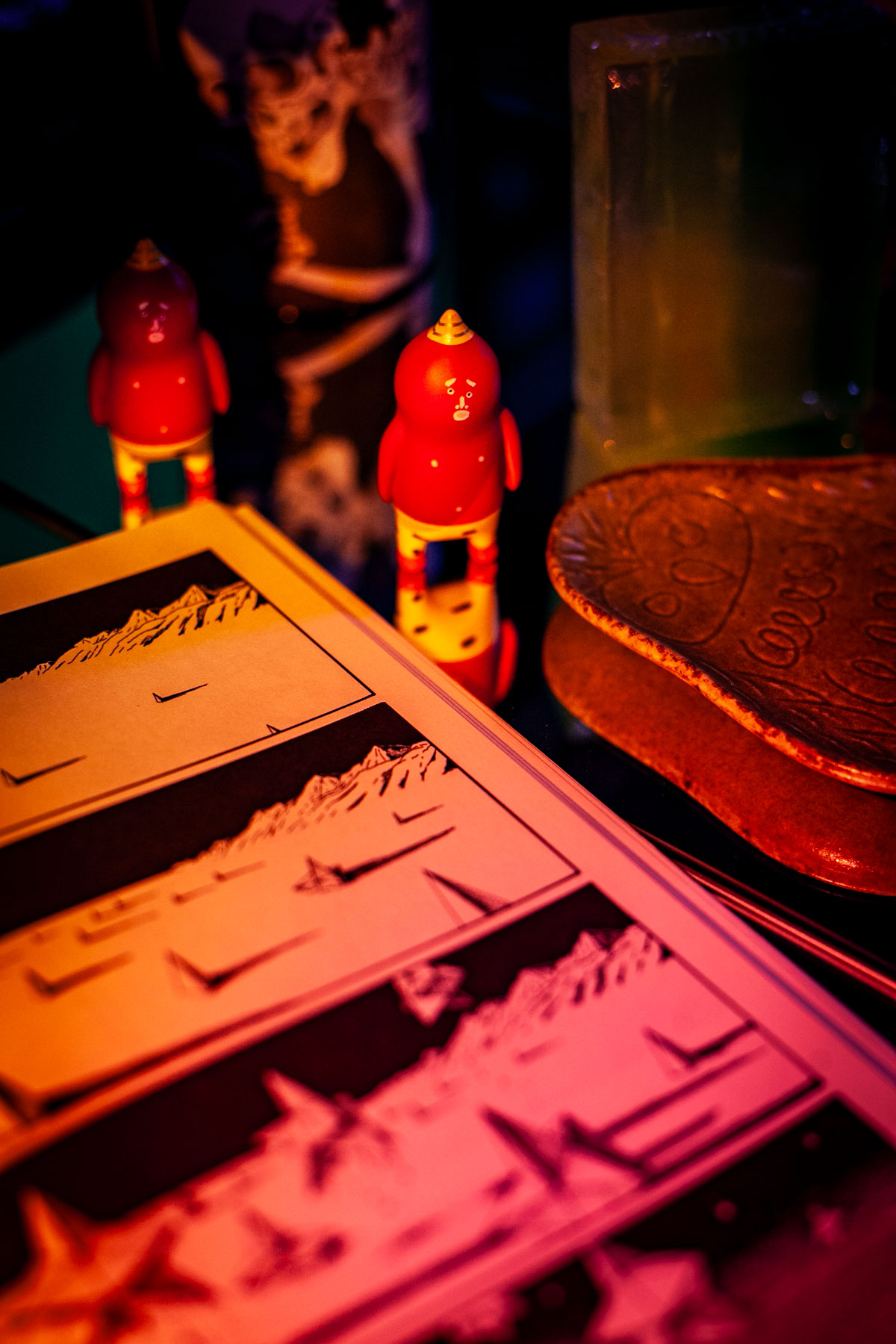 two oni demon vinyl toys looking up at you & surrounded by objects