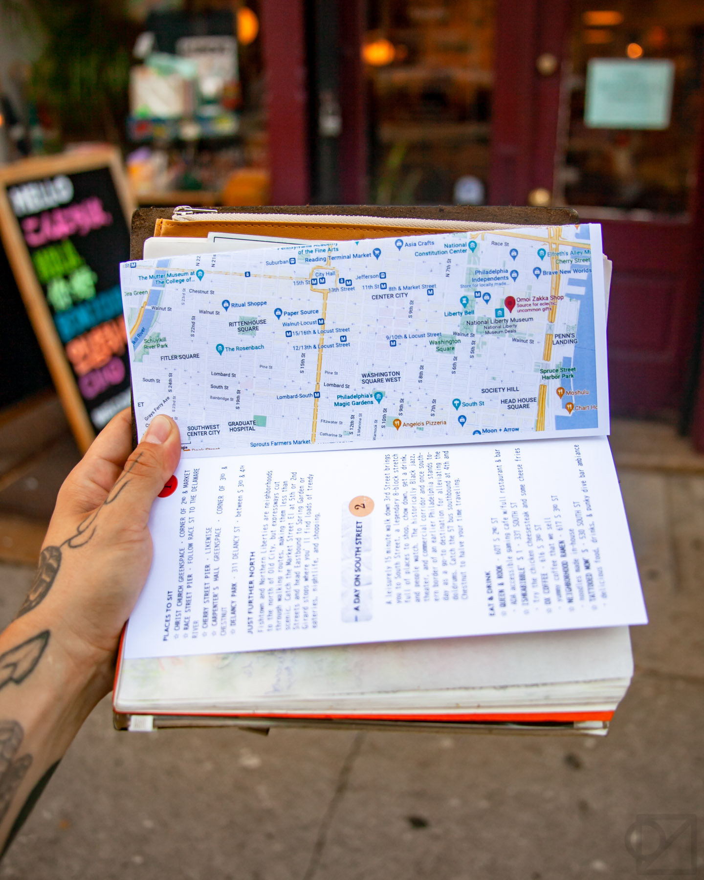 person holding a pamphlet with map in front of a store